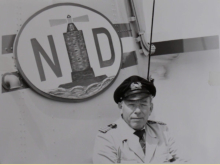 Kapitän Werner Schaal vor seinem Reederei-Emblem